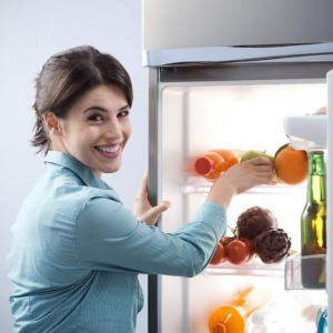 Mujer ingresando alimentos en un refrigerador