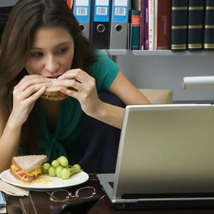 Mujer comiendo frente al computador